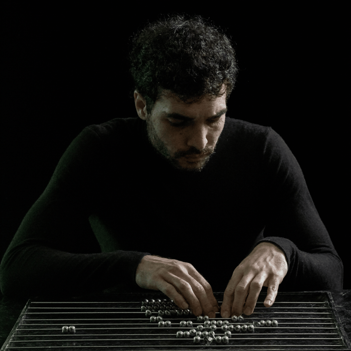 Kassem Kazal slides steel beads across a chrome abacus at a dark stone table